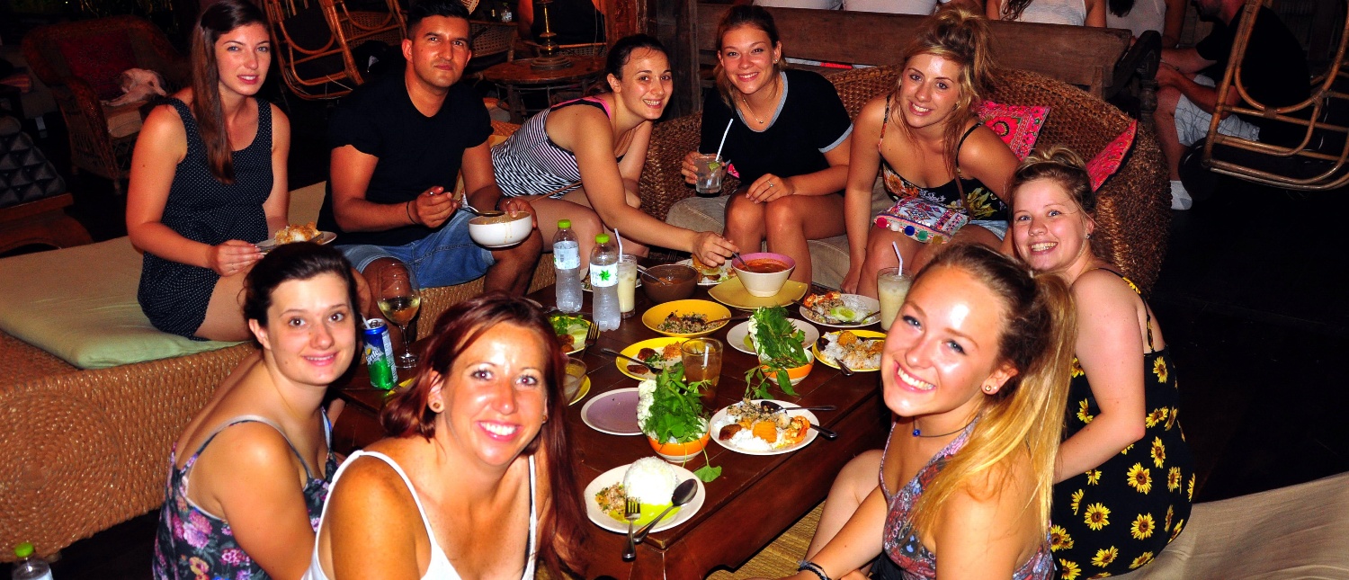 A group of happy backpackers enjoys a traditional Thai-style welcome dinner in Bangkok.
