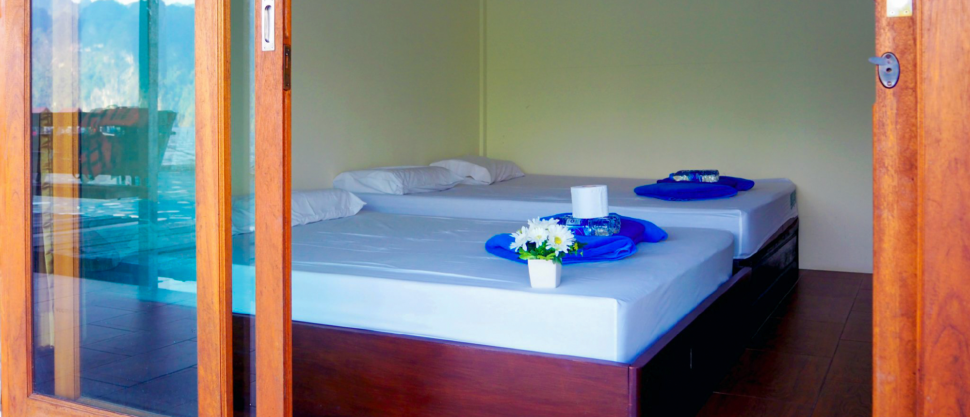 A clean, inviting floating bungalow room with two beds and a scenic view in Khao Sok National Park.