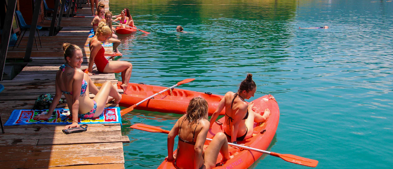 Travelers enjoy kayaking and swimming from floating bungalows in Khao Sok National Park, Thailand.