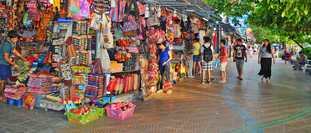 Tourists browse colorful souvenir stalls along a lively street market in Krabi, Thailand.