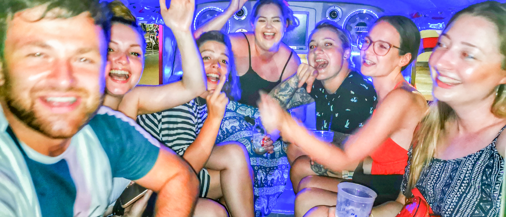 A group of happy young friends laughing and celebrating together in a lively Krabi nightlife setting.