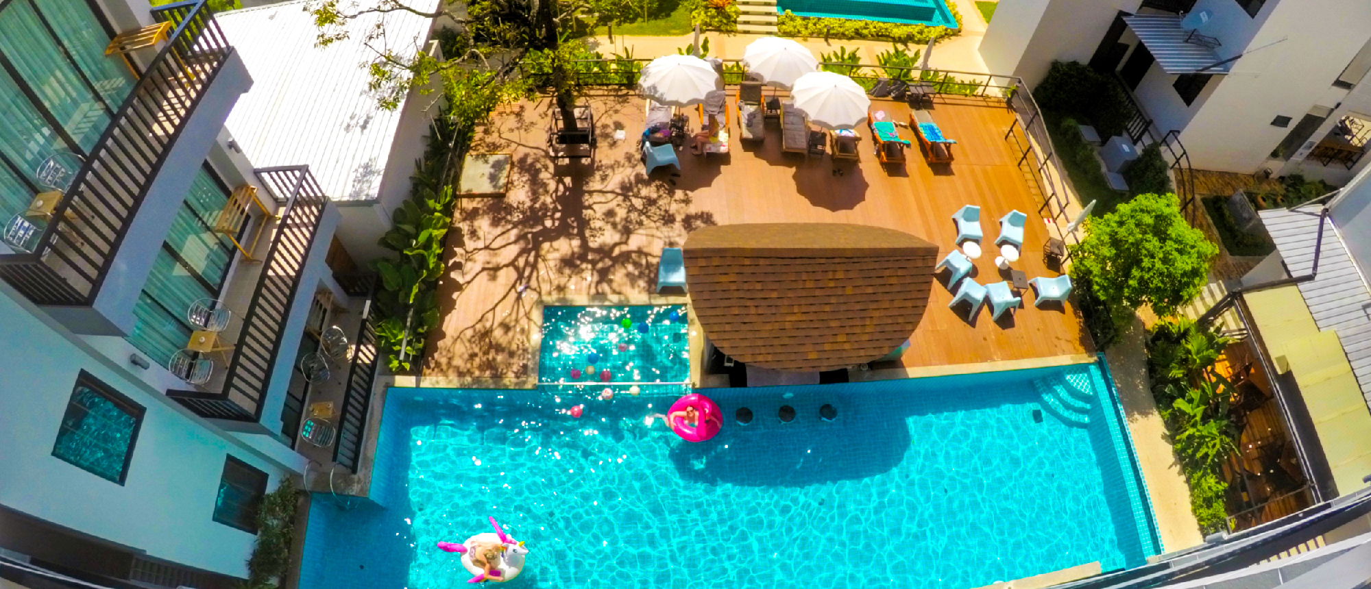 An aerial view of a vibrant resort pool in Krabi, Thailand, with people relaxing on floats.