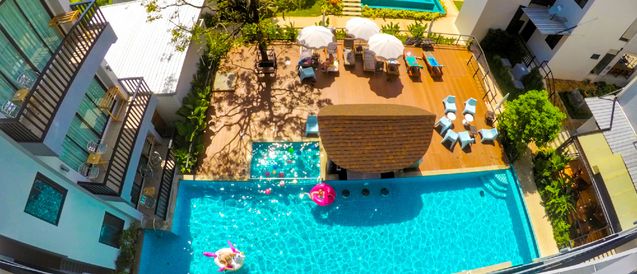 An aerial view of a vibrant resort pool in Krabi, Thailand, with people relaxing on floats.