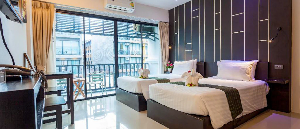 Inviting modern hotel room with two single beds, decorative towels, and a balcony in Krabi.
