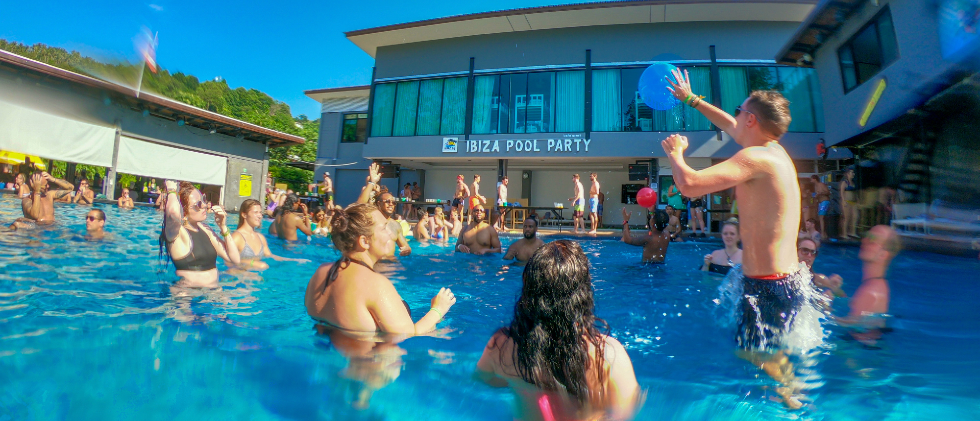A lively group of backpackers enjoying an Ibiza pool party in Koh Phi Phi, Thailand.
