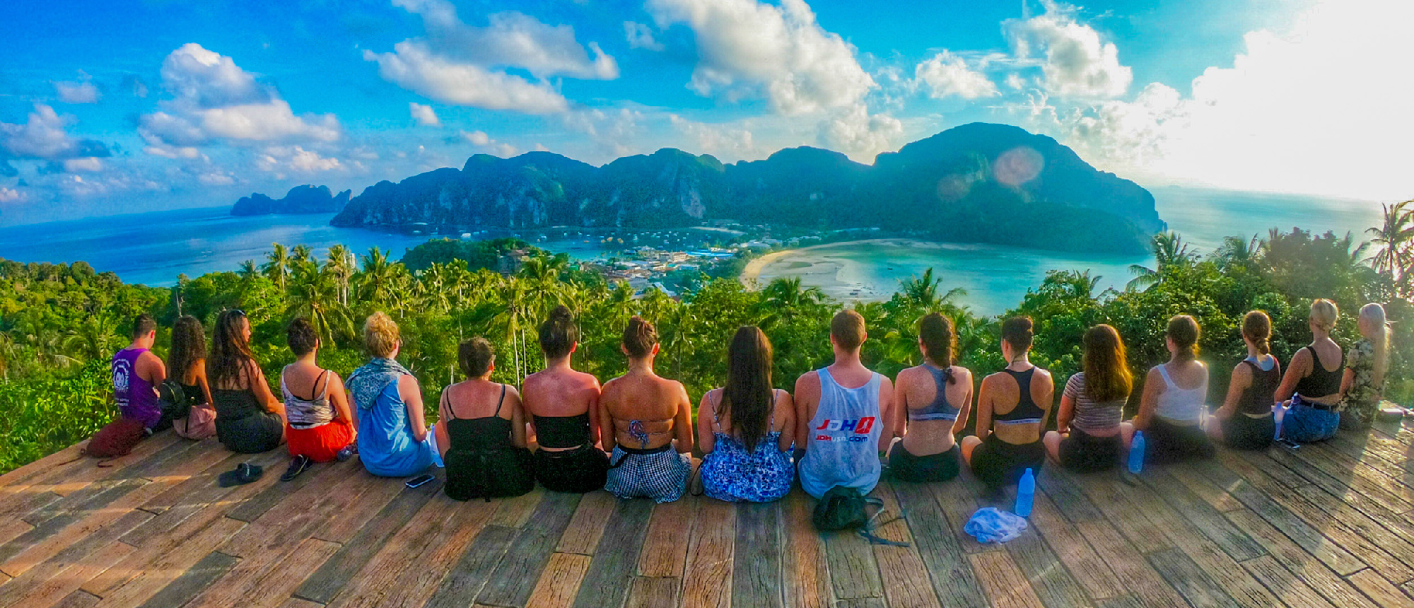 A group of friends sits on a viewpoint, admiring the stunning turquoise bays and islands of Koh Phi Phi.