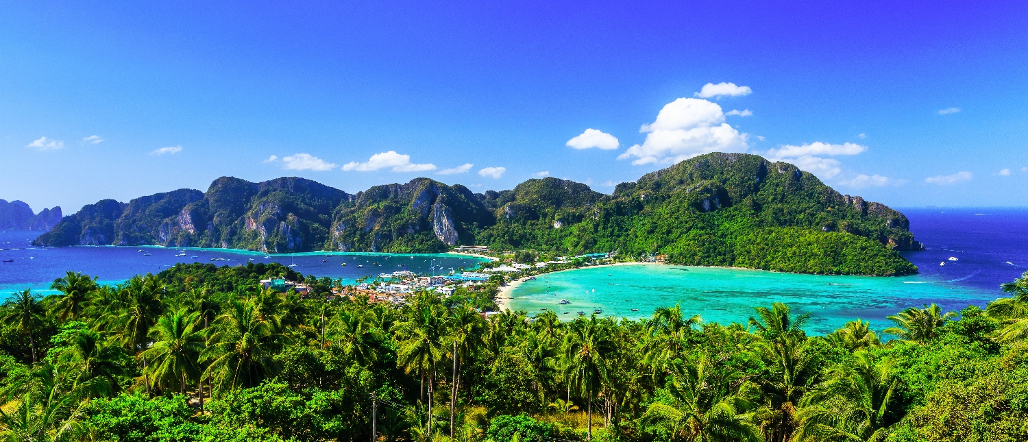 Panoramic view of Phi Phi Islands, featuring lush green mountains, turquoise water, and a sandy beach.