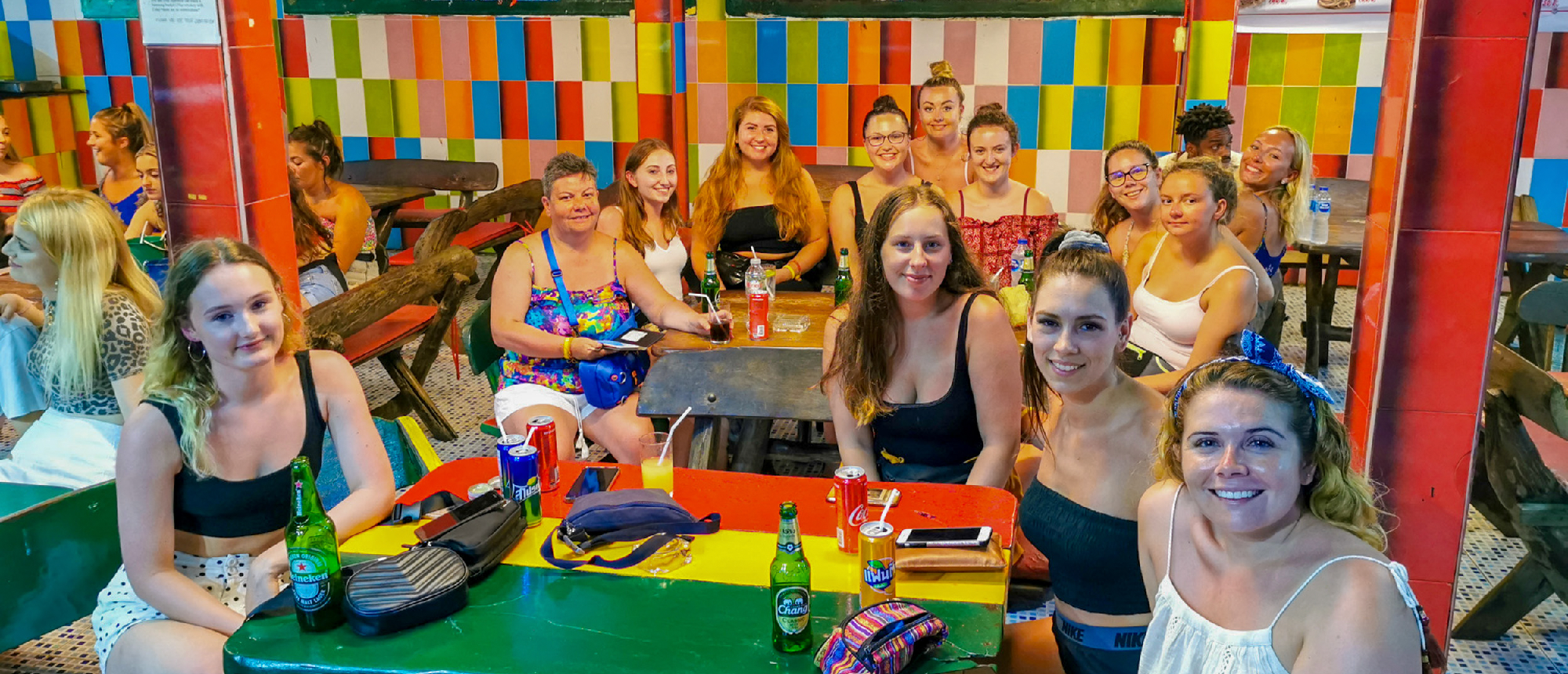 A group of smiling women enjoying drinks and socializing at a vibrant bar in Phuket, Thailand.