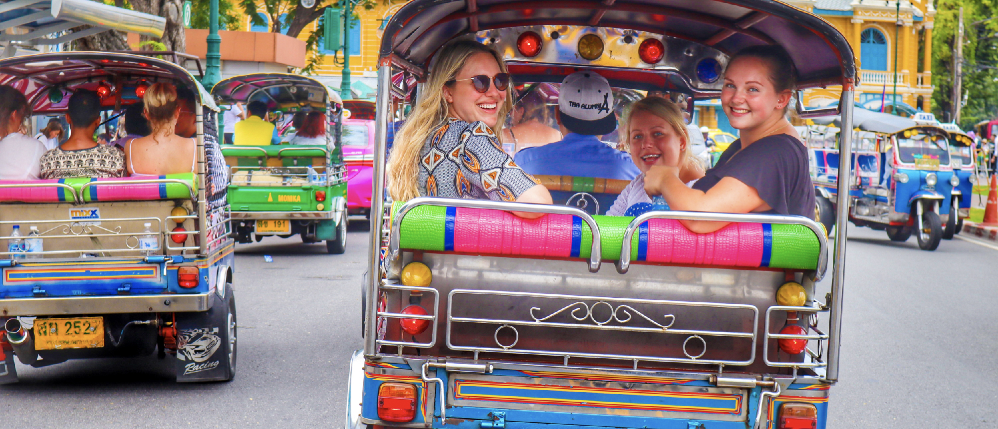 Smiling travelers enjoy a fun tuk-tuk ride through the lively streets of Bangkok.