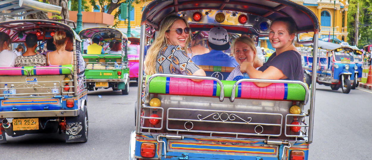 Smiling travelers enjoy a fun tuk-tuk ride through the lively streets of Bangkok.
