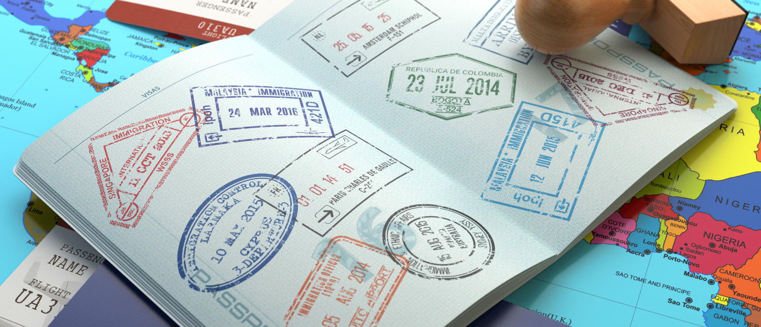 An open passport full of visa stamps, lying on a world map