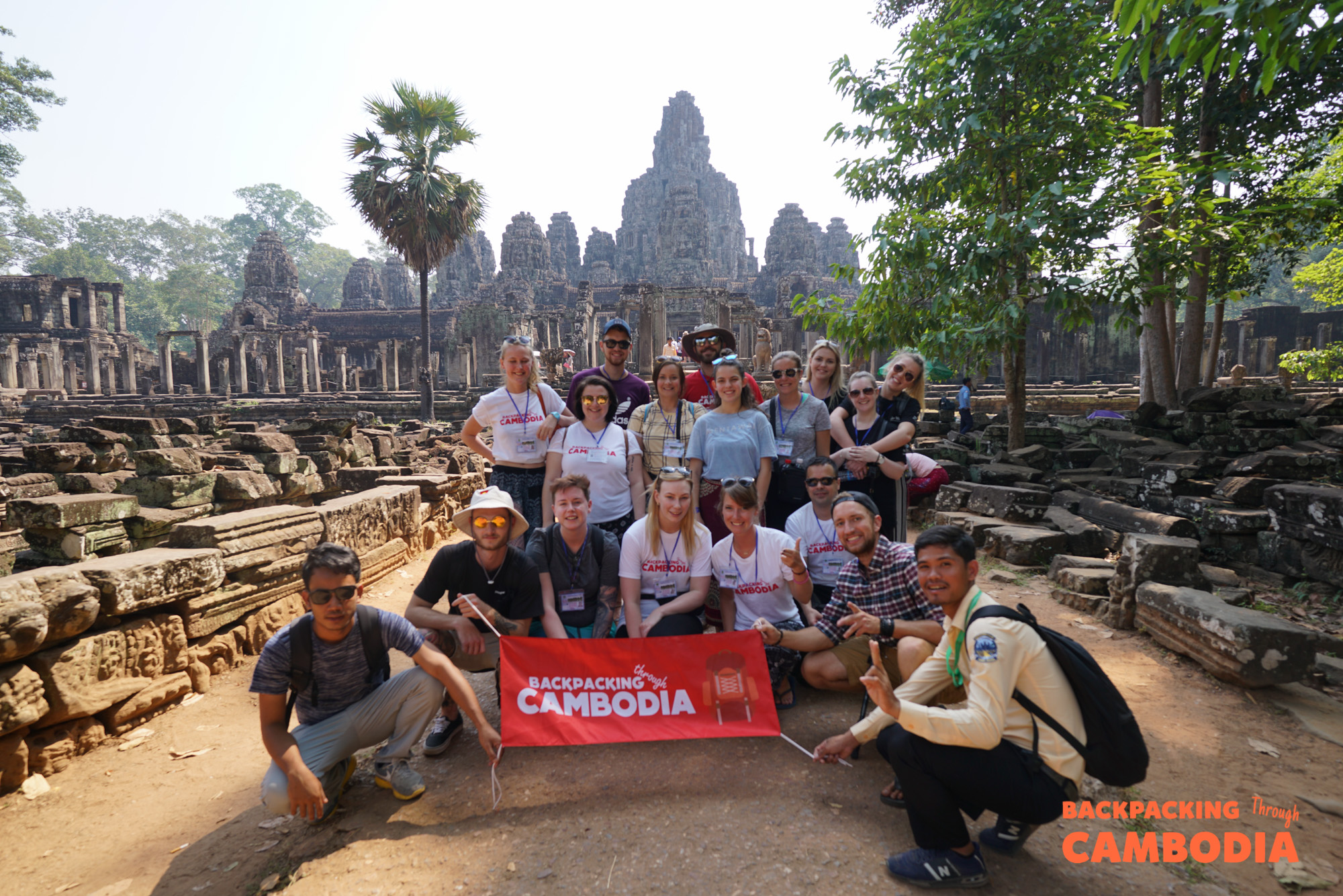 A group of backpackers holding a Cambodia banner in front of Angkor Wat