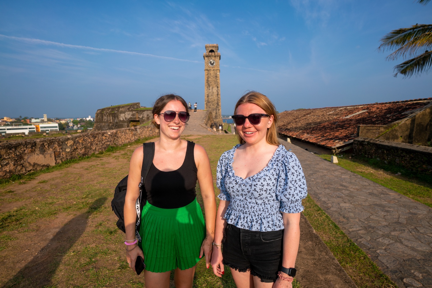 Two smiling women enjoying a sunny day exploring the historic Galle Fort in Sri Lanka.