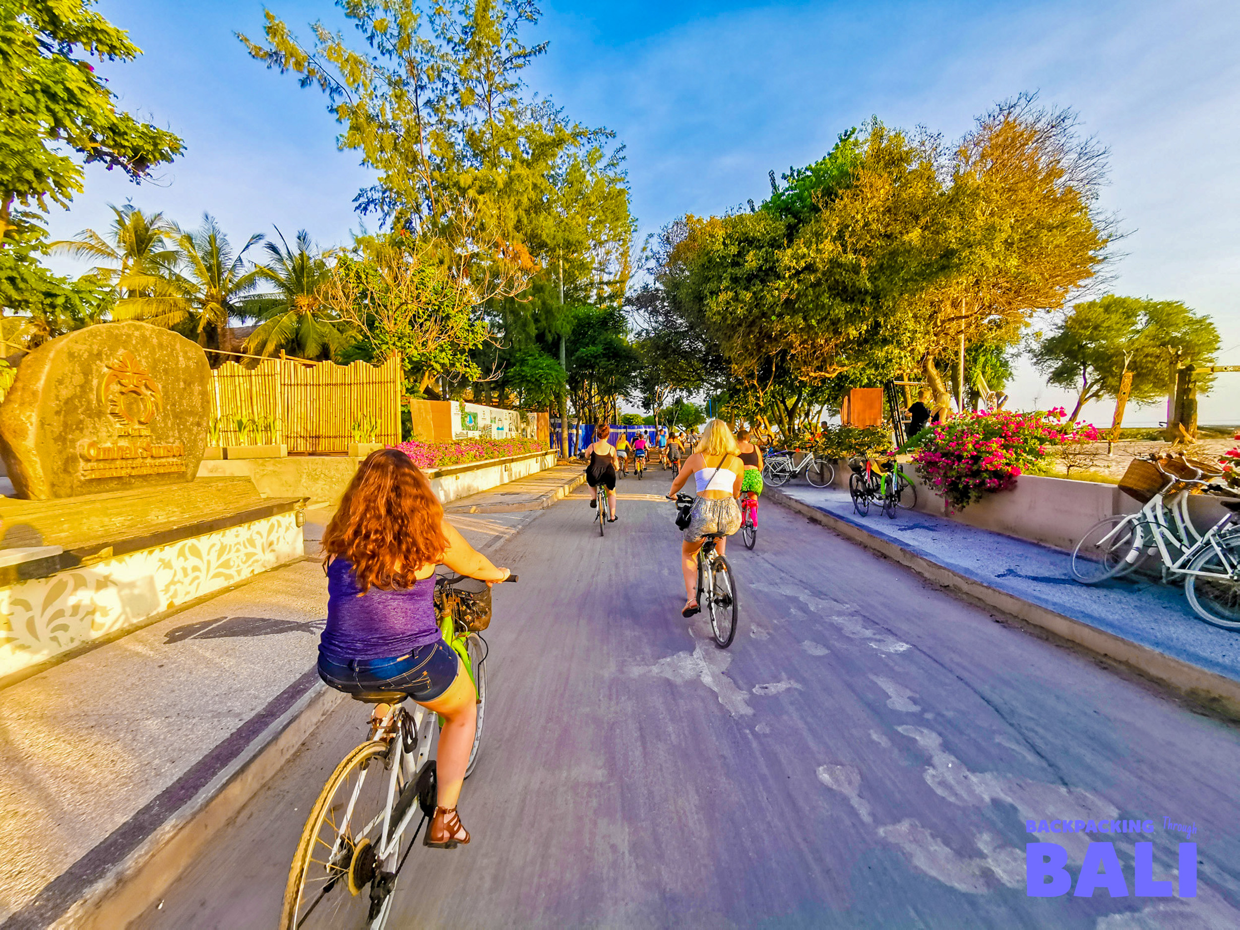 Tourists cycle along a sunny coastal path on Gili Trawangan, enjoying the island's relaxed vibe.