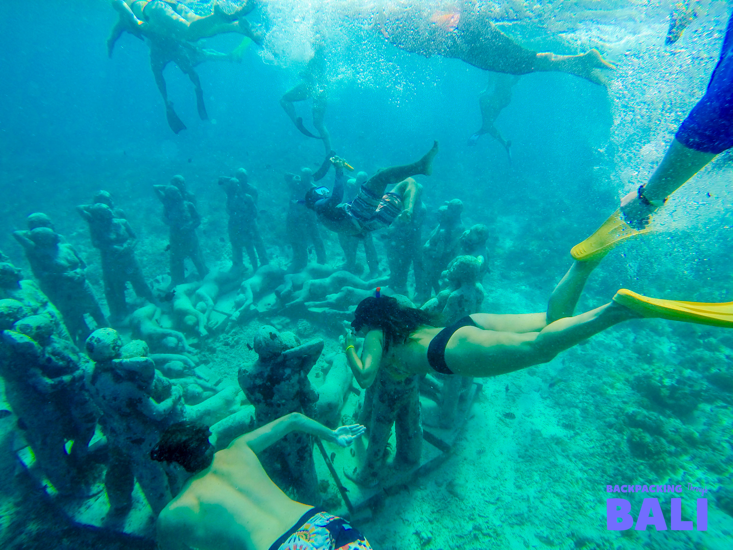 Snorkelers explore the stunning underwater art installation off Gili Meno, surrounded by clear blue water.