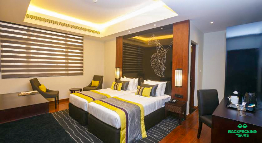 A modern hotel room in Colombo with two comfortable beds and stylish yellow and grey decor.