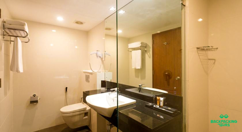 A clean and modern bathroom with a white sink, toilet, and glass shower partition in Colombo.