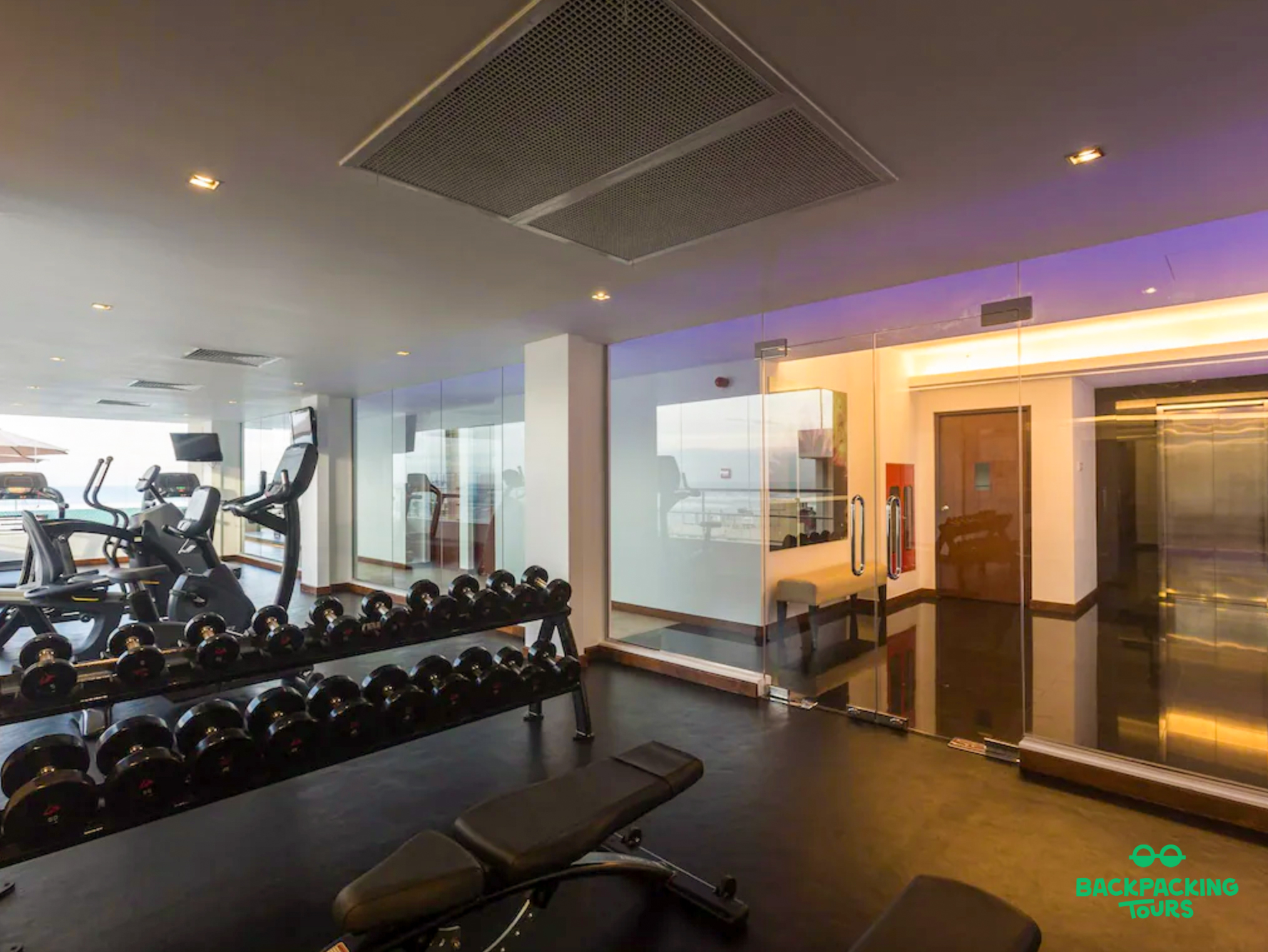 A modern hotel gym in Colombo with weights, cardio machines, and large windows.