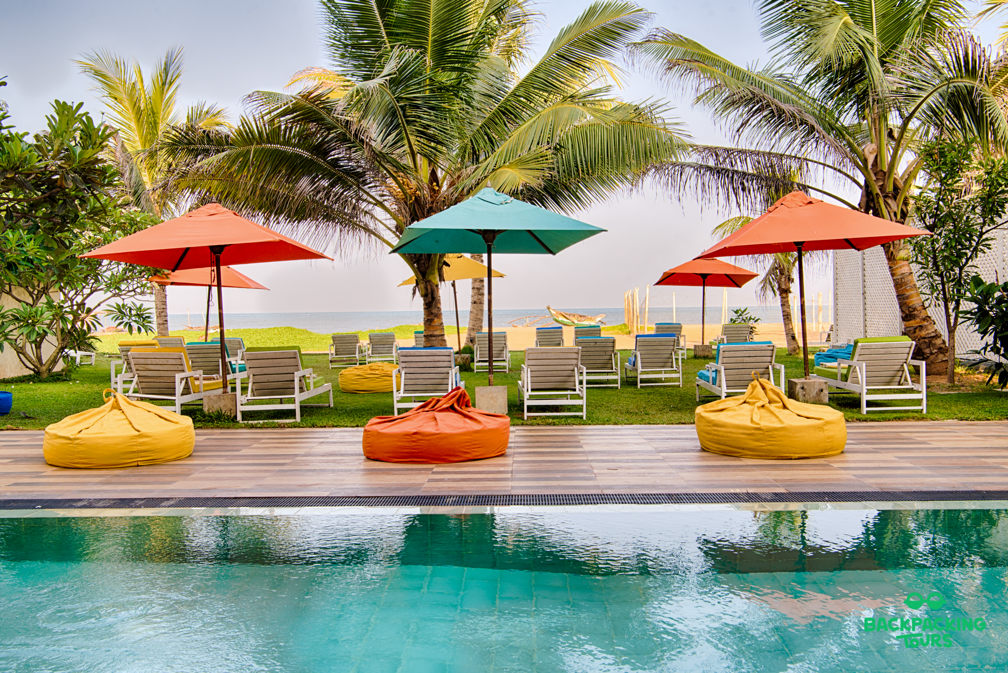 Relax by the pool with colorful beanbags and umbrellas, overlooking the beach in Colombo, Sri Lanka.
