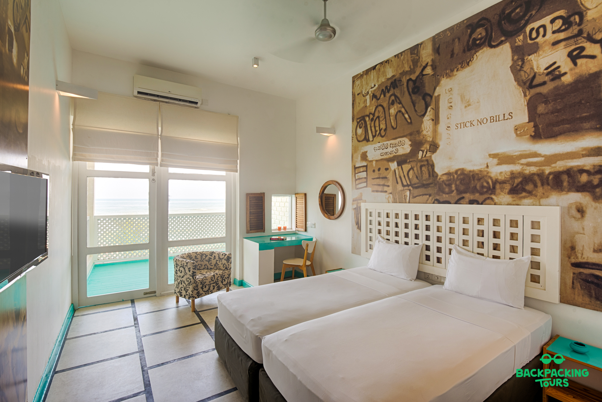 A stylish hotel room in Sri Lanka with twin beds and a balcony offering ocean views.
