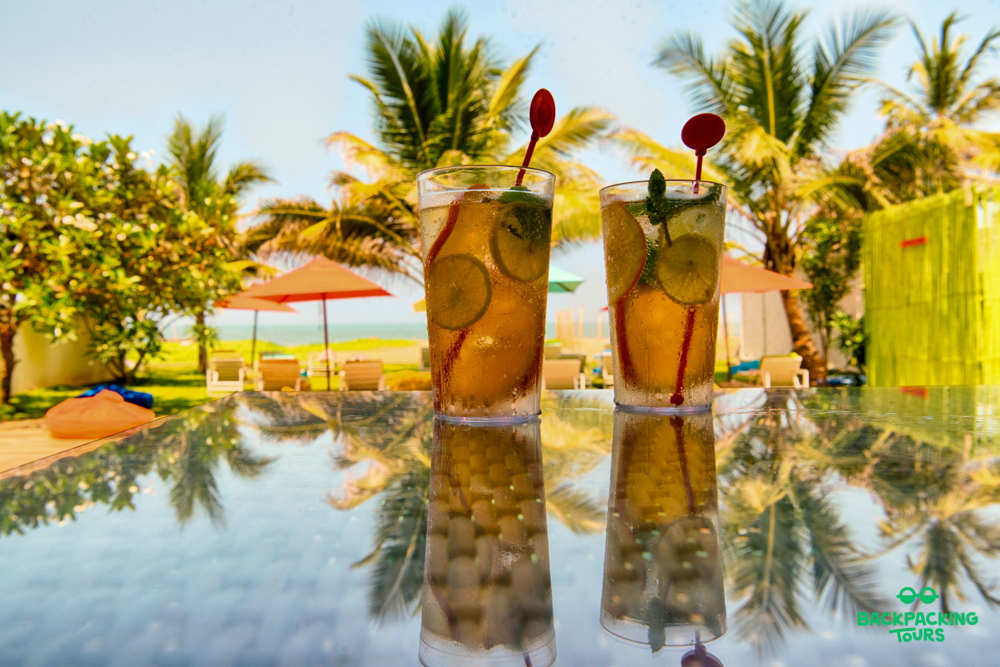 Two refreshing cocktails on the edge of an infinity pool overlooking a tropical beach in Sri Lanka.