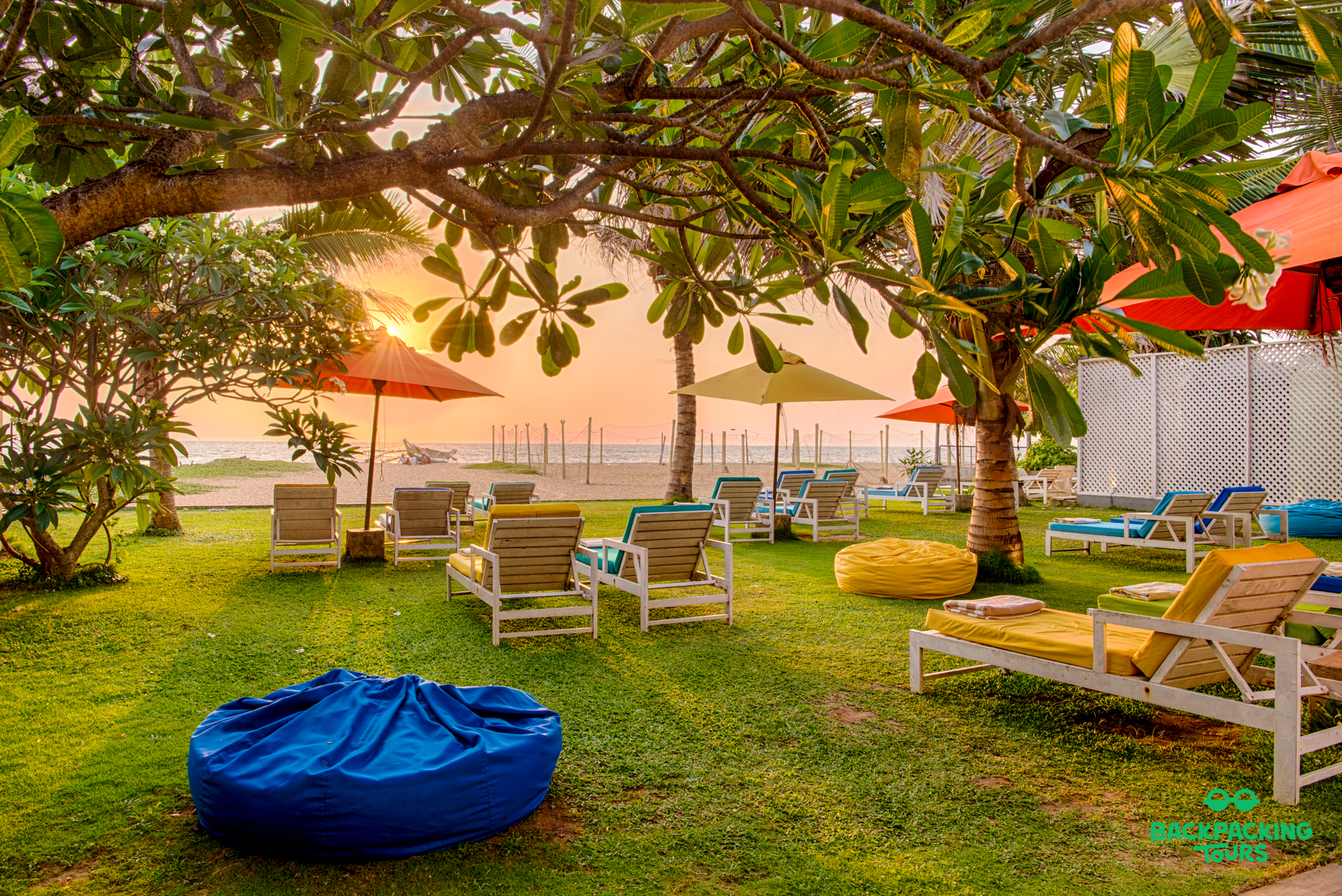 Relaxing tropical resort lawn with colorful lounge chairs by the beach at sunset in Sri Lanka.