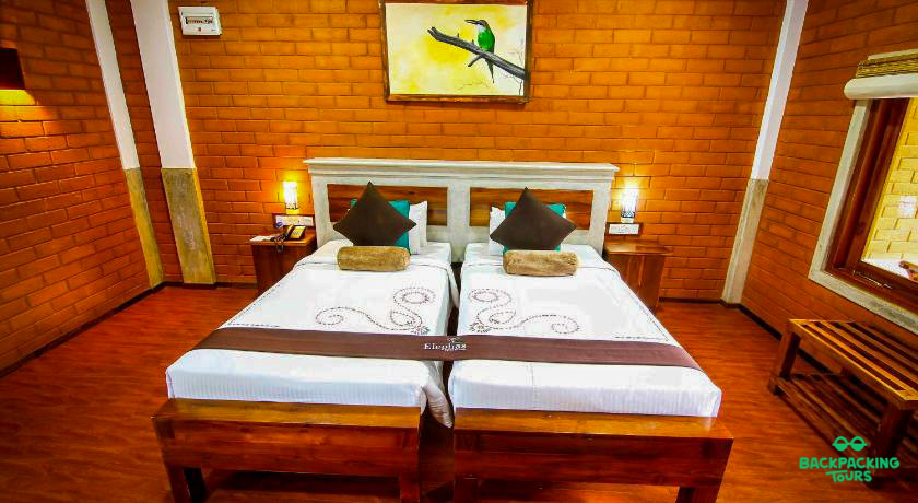Clean and cozy twin room in Dambulla, Sri Lanka, featuring brick walls and wooden furniture.