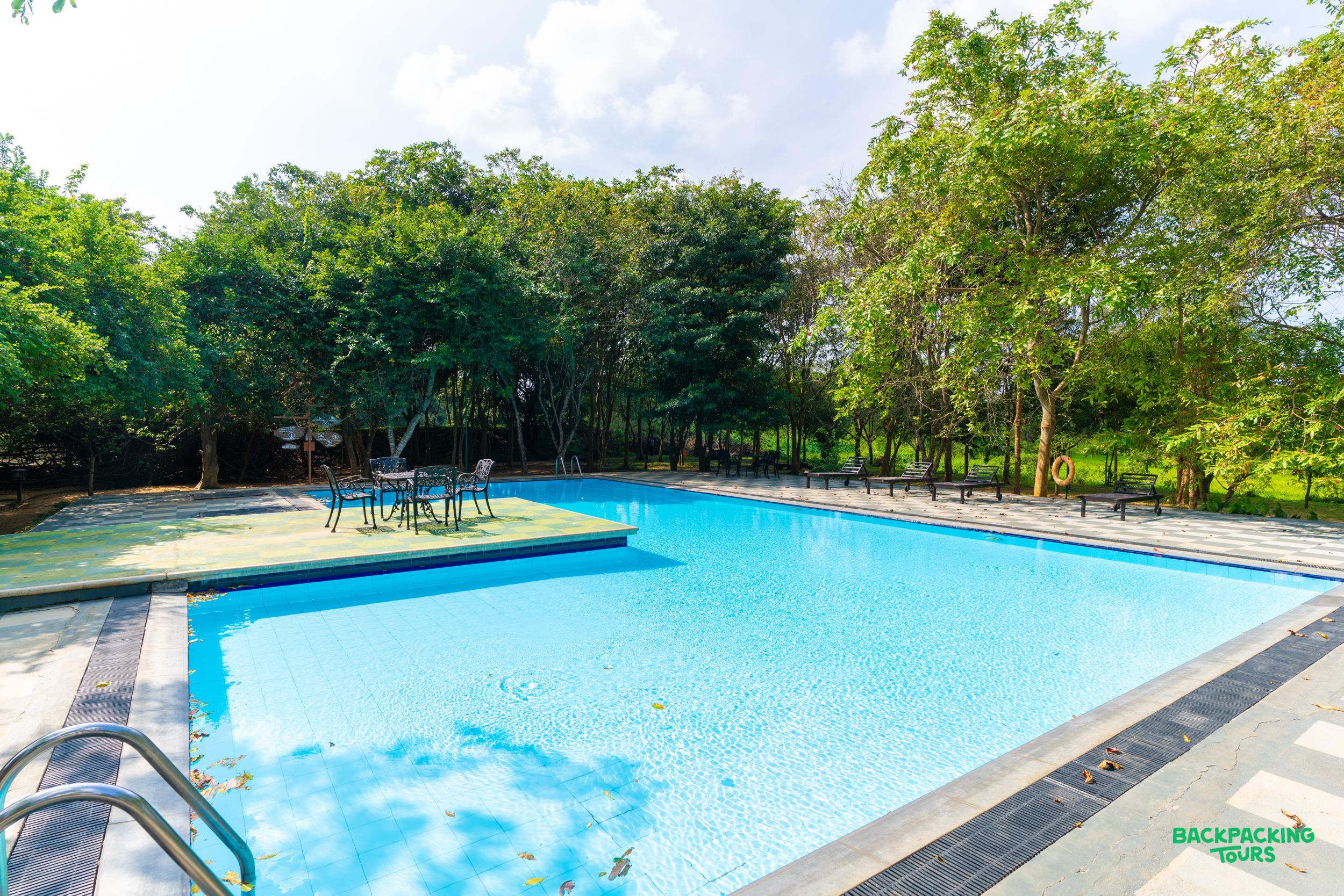 A refreshing blue swimming pool at a tropical resort in Sri Lanka, surrounded by lush green trees.
