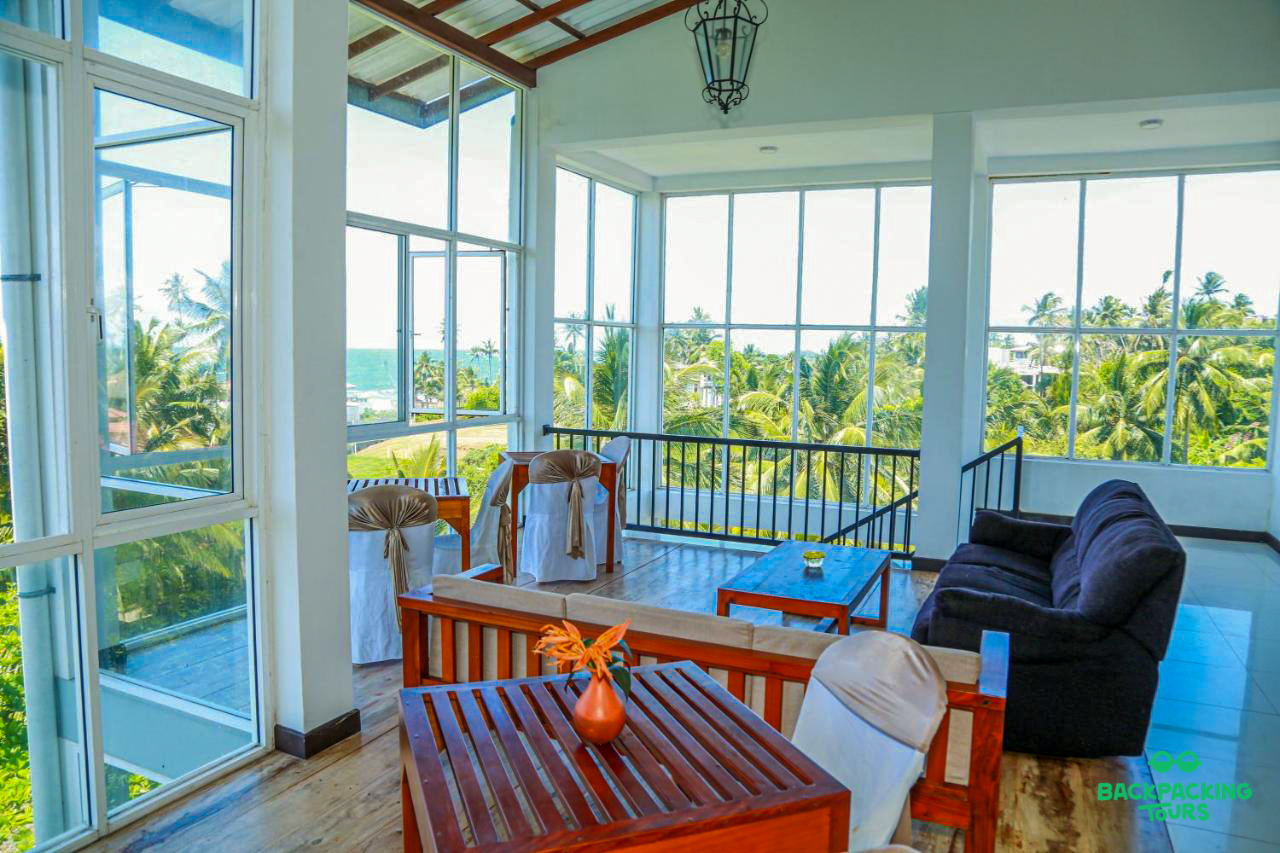 Relax in this spacious lounge area with stunning views of Weligama beach and palm trees.