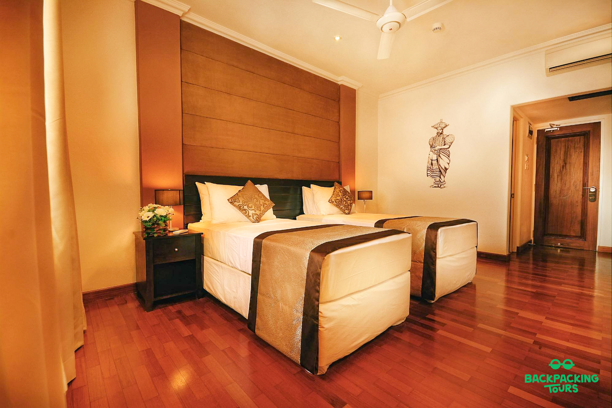 A comfortable hotel room with two single beds, hardwood floor, and modern decor in Sigiriya.