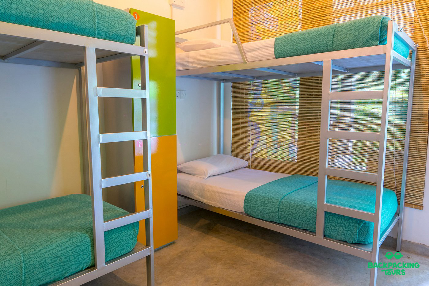 A clean and modern hostel dorm room with two bunk beds and colorful lockers in Ella, Sri Lanka.