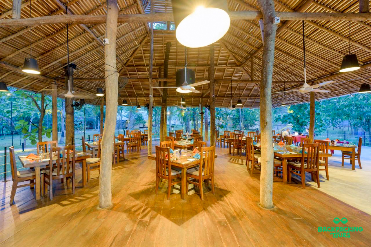 A spacious open-air restaurant with a thatched roof and wooden tables at an accommodation in Weligama.