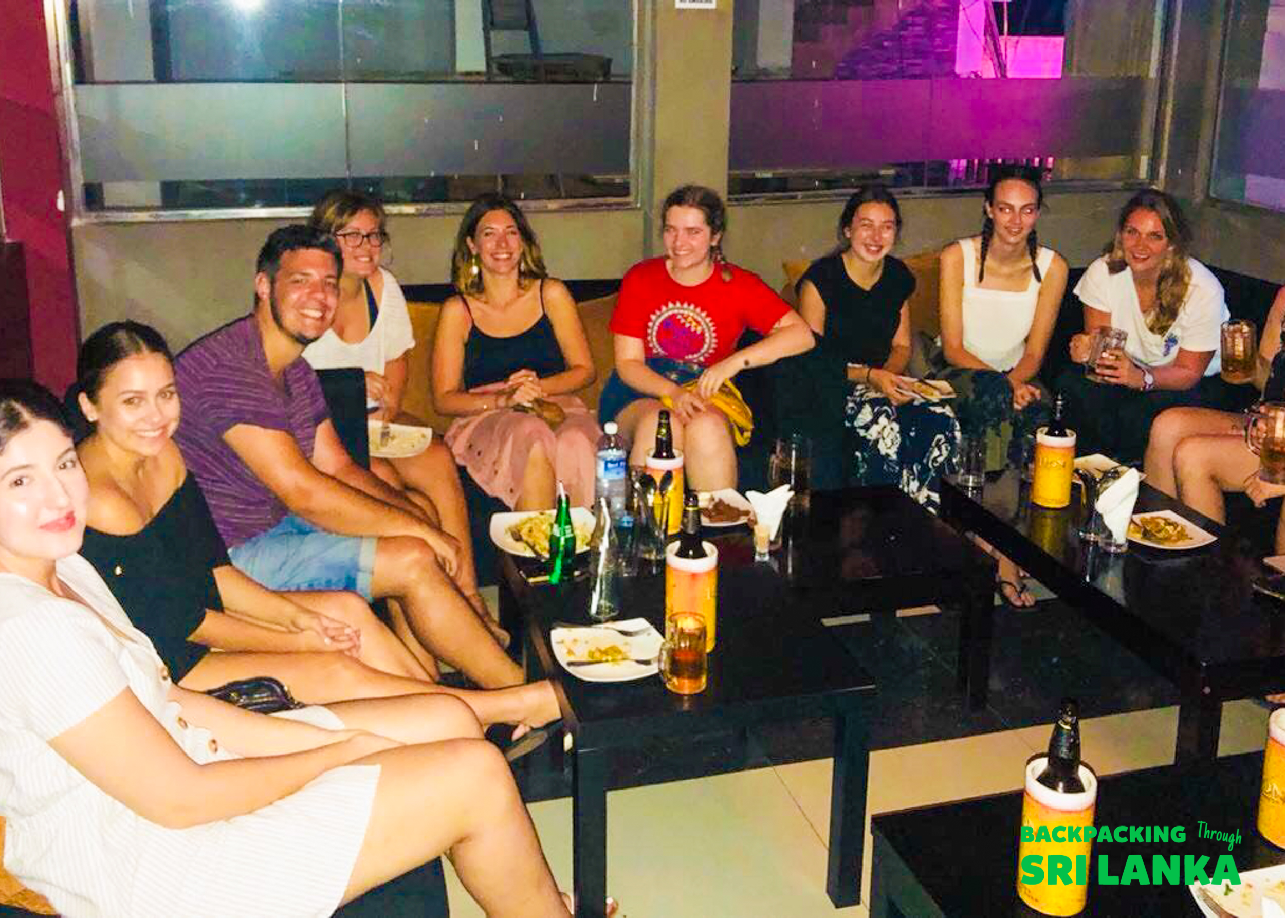 A group of young backpackers enjoying drinks and conversation during a night out in Colombo.