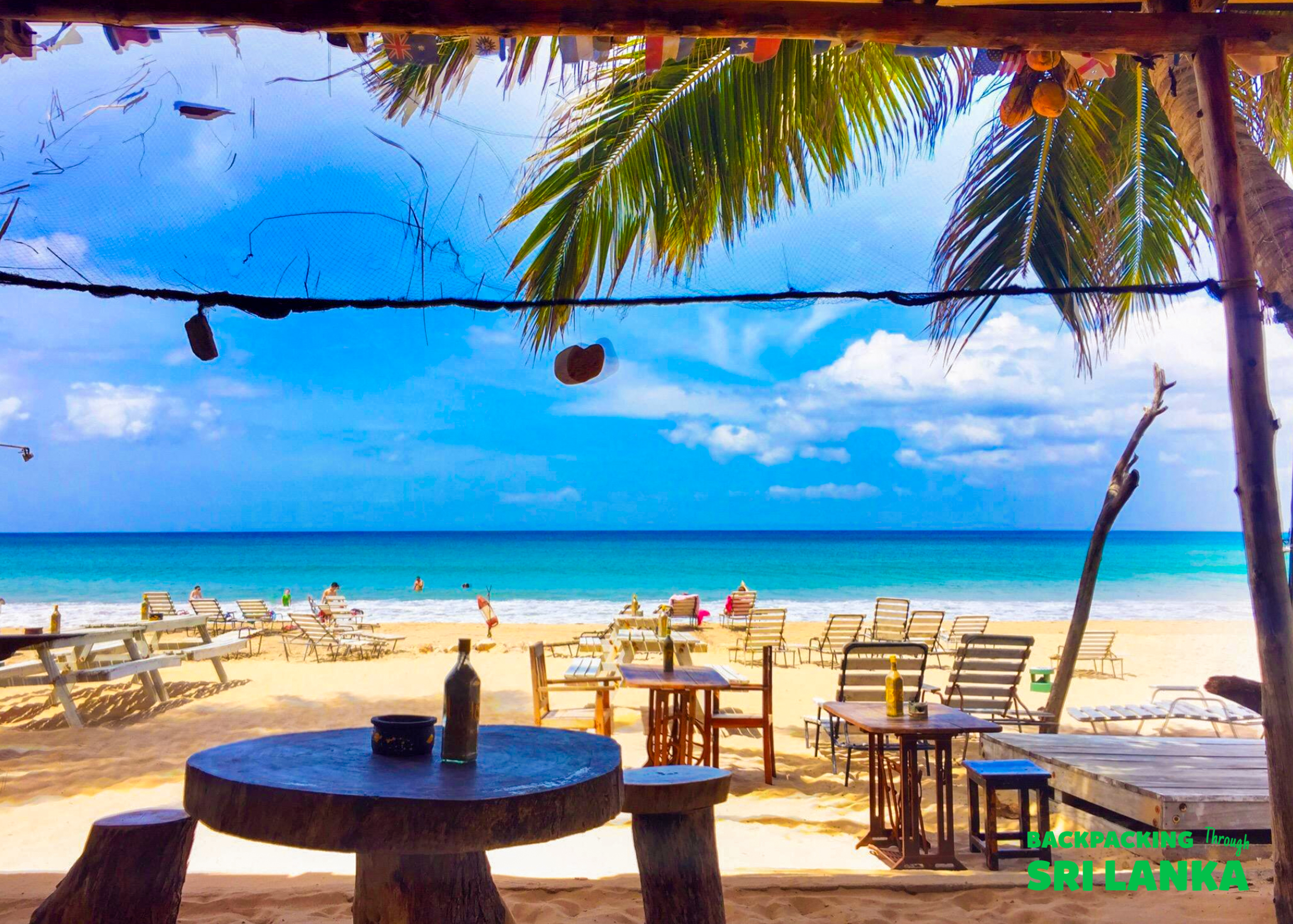 A relaxing view from a rustic beach bar overlooking the sandy Weligama beach and turquoise ocean.