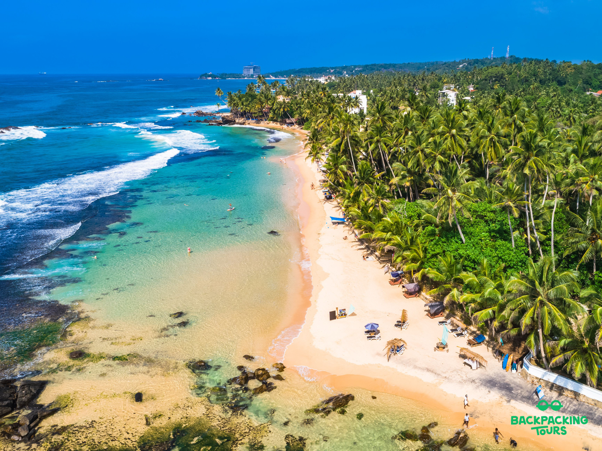 Aerial view of a stunning tropical beach with turquoise water, white sand, and palm trees in Unawatuna.