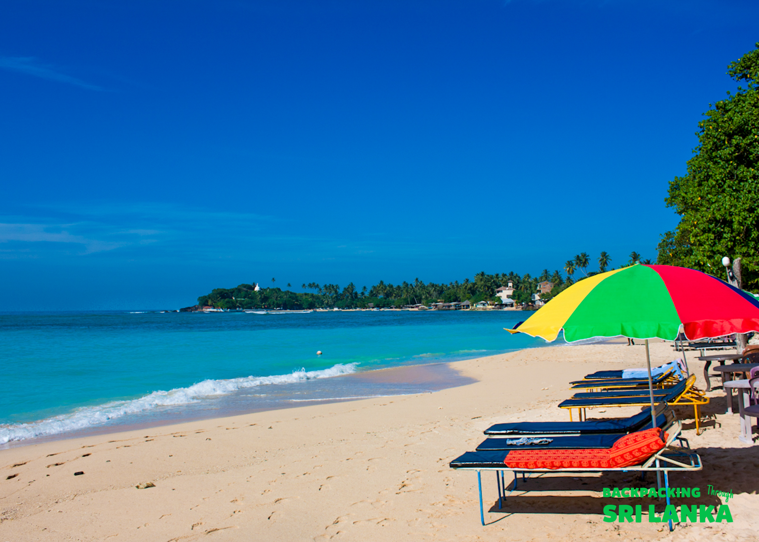Relaxing on the beautiful sandy beach of Unawatuna with turquoise water and a colorful umbrella.