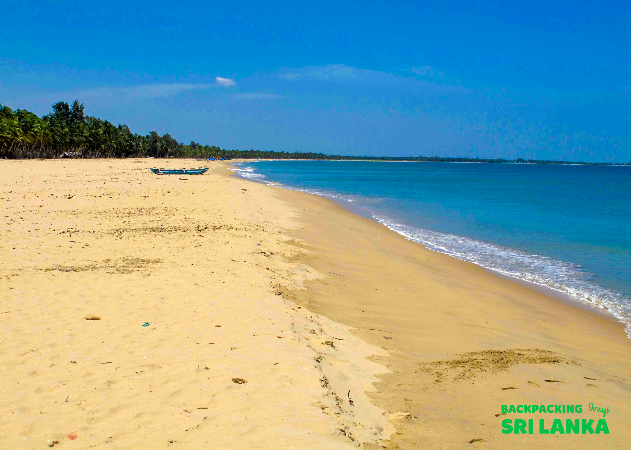 Tranquil Unawatuna beach with golden sand, clear blue water, and a lone fishing boat.