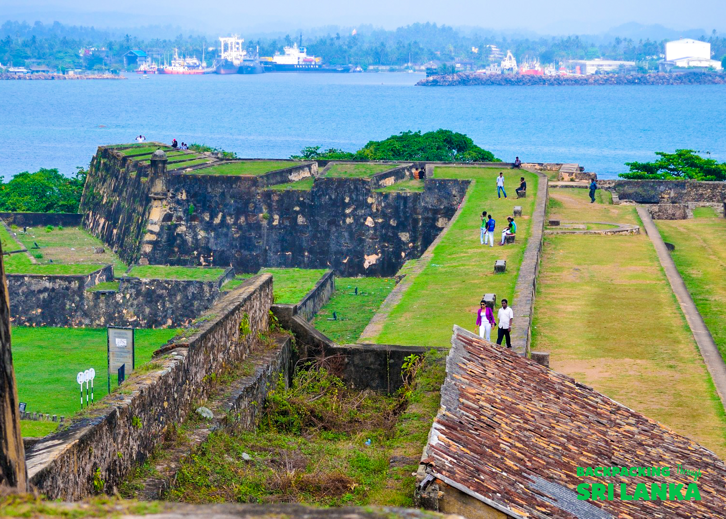 Tourists walk on the grassy ramparts of the historic Galle Dutch Fort overlooking the bay.