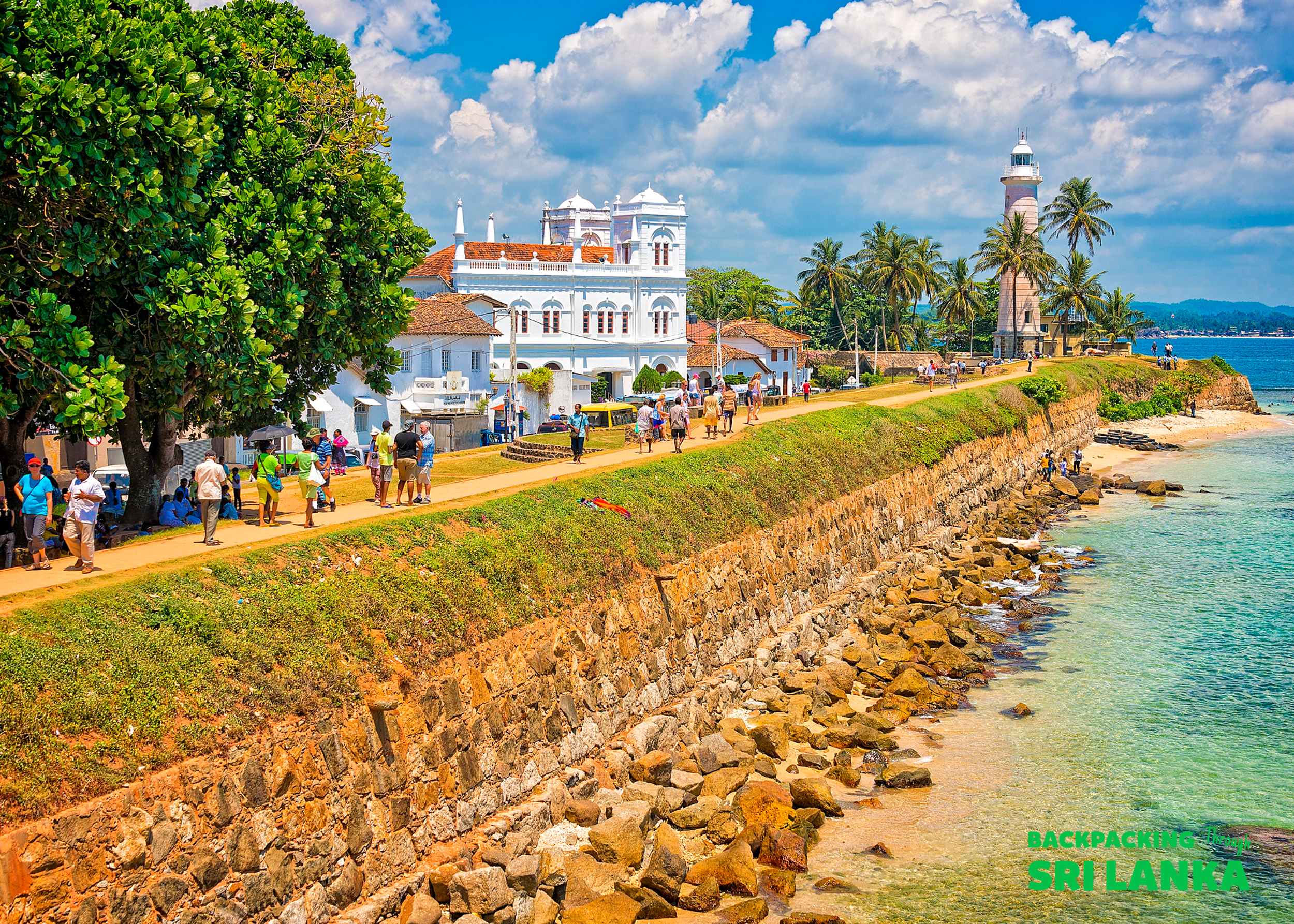 People stroll along the historic Galle Fort walls, enjoying views of the lighthouse and ocean in Sri Lanka.