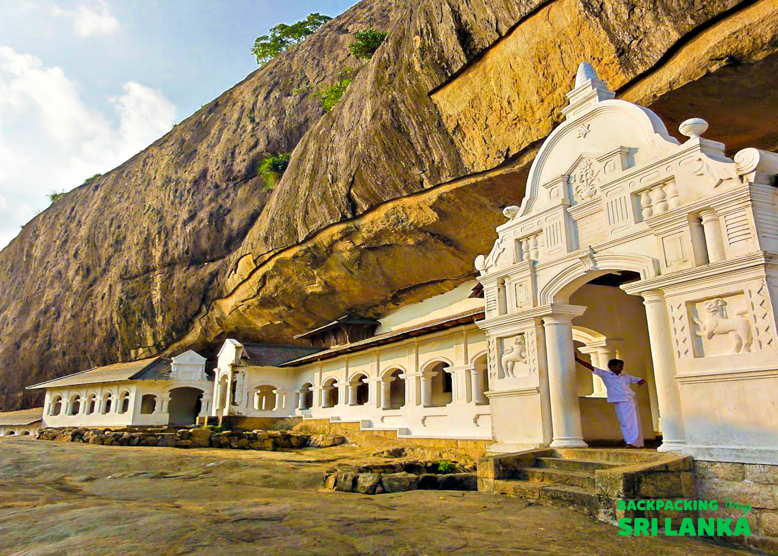 A person stands at the ornate entrance of the Golden Temple of Dambulla in Sri Lanka.