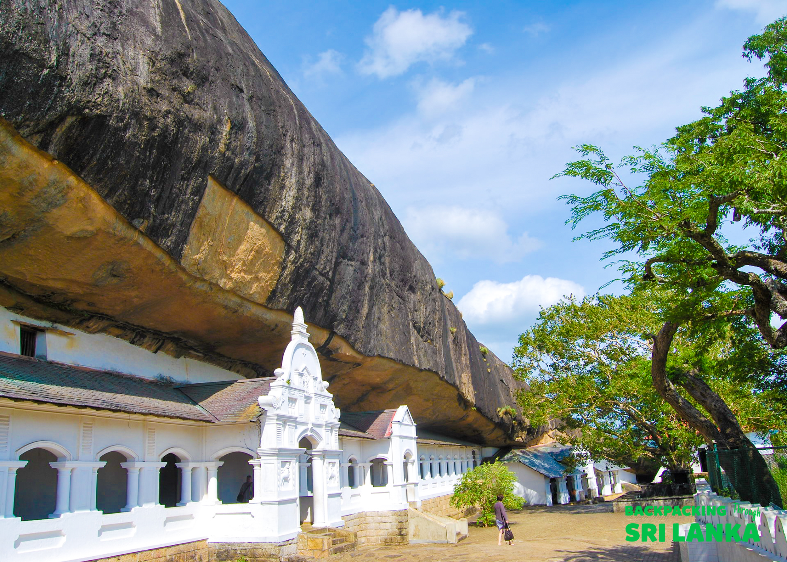 The Dambulla Cave Temple complex, with white buildings built under a massive rock cliff.