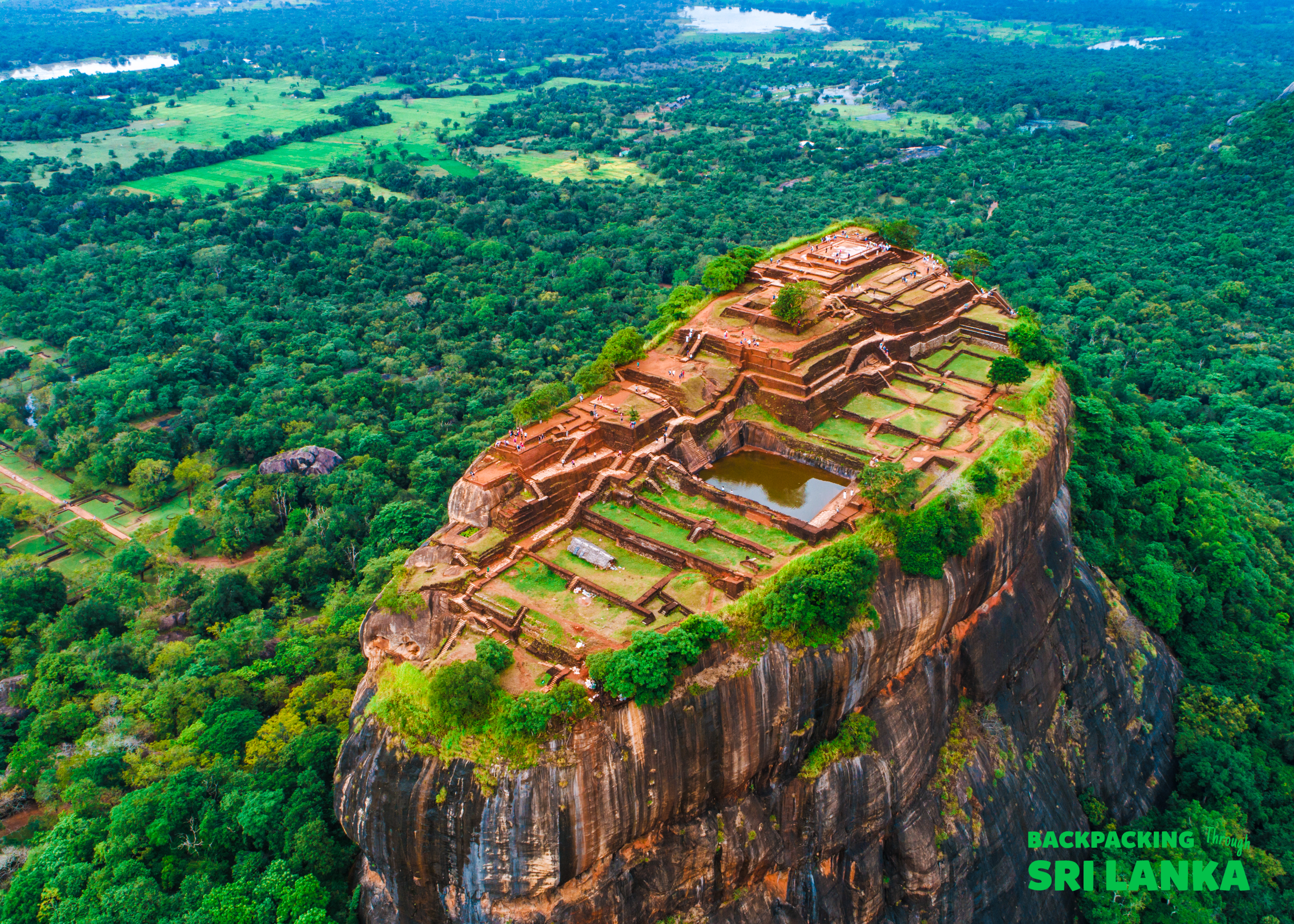 The ancient Sigiriya Rock fortress, with its terraced ruins, stands majestically above the lush Sri Lankan jungle.
