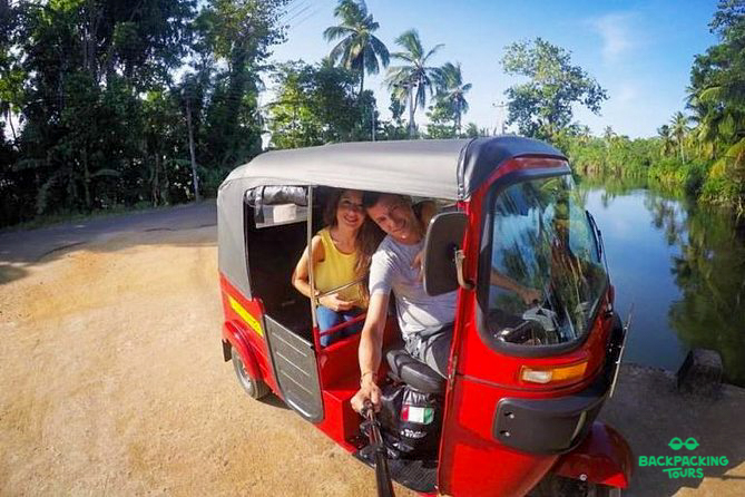 Smiling travelers explore the rural landscapes of Sigiriya by tuk-tuk, enjoying a village tour.