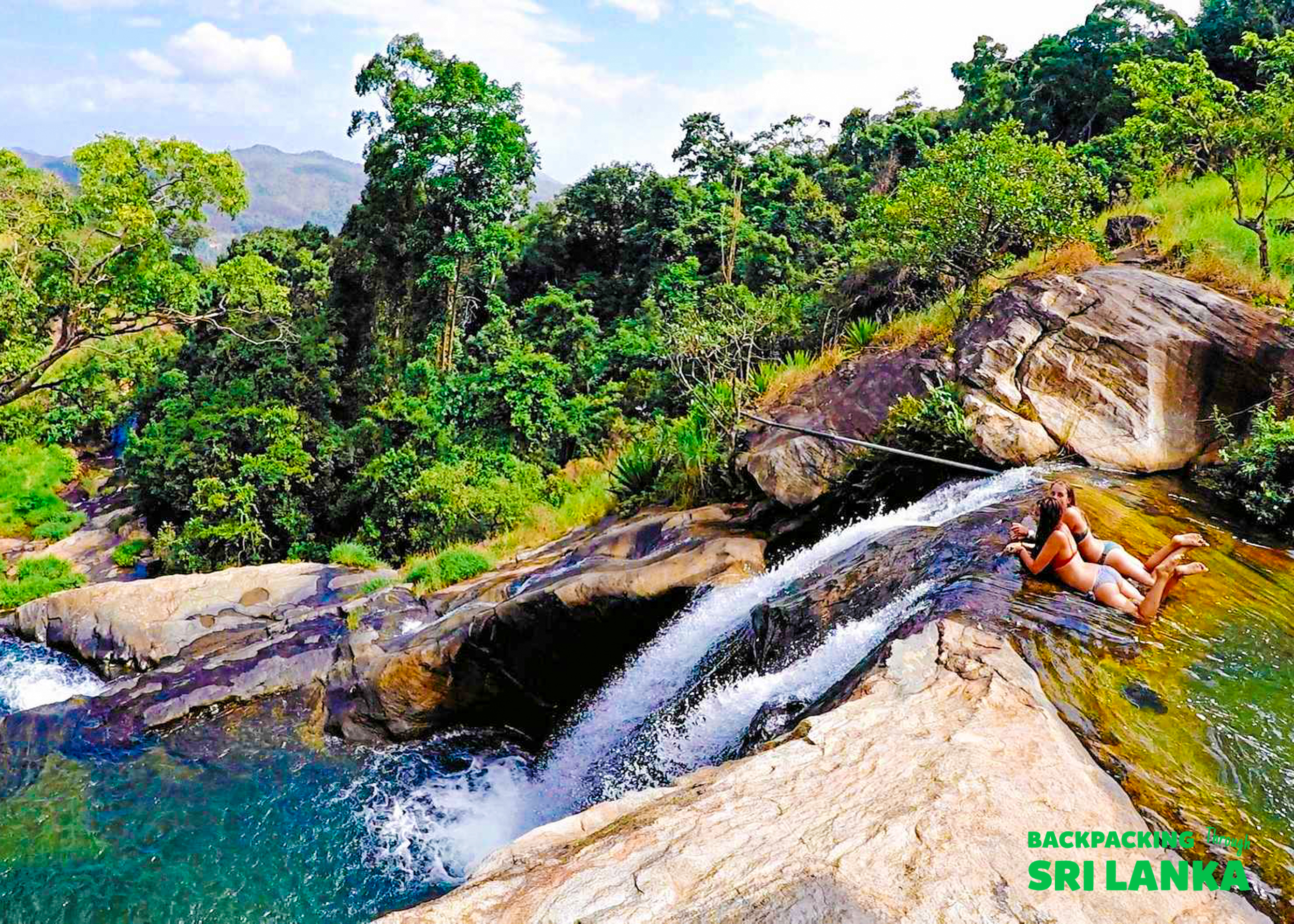 Two women relax on rocks beside the cascading waters of Diyaluma Falls, Sri Lanka.