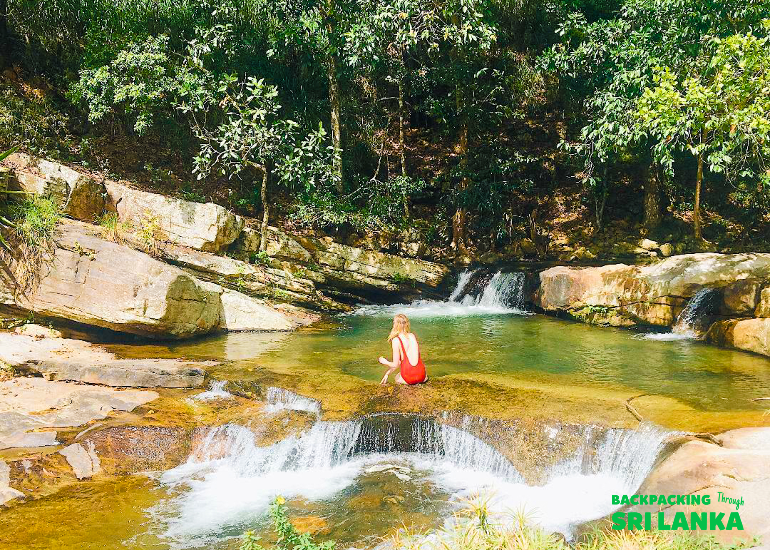 A woman in a red swimsuit sits in the clear, refreshing pools of Diyaluma Falls, Sri Lanka.
