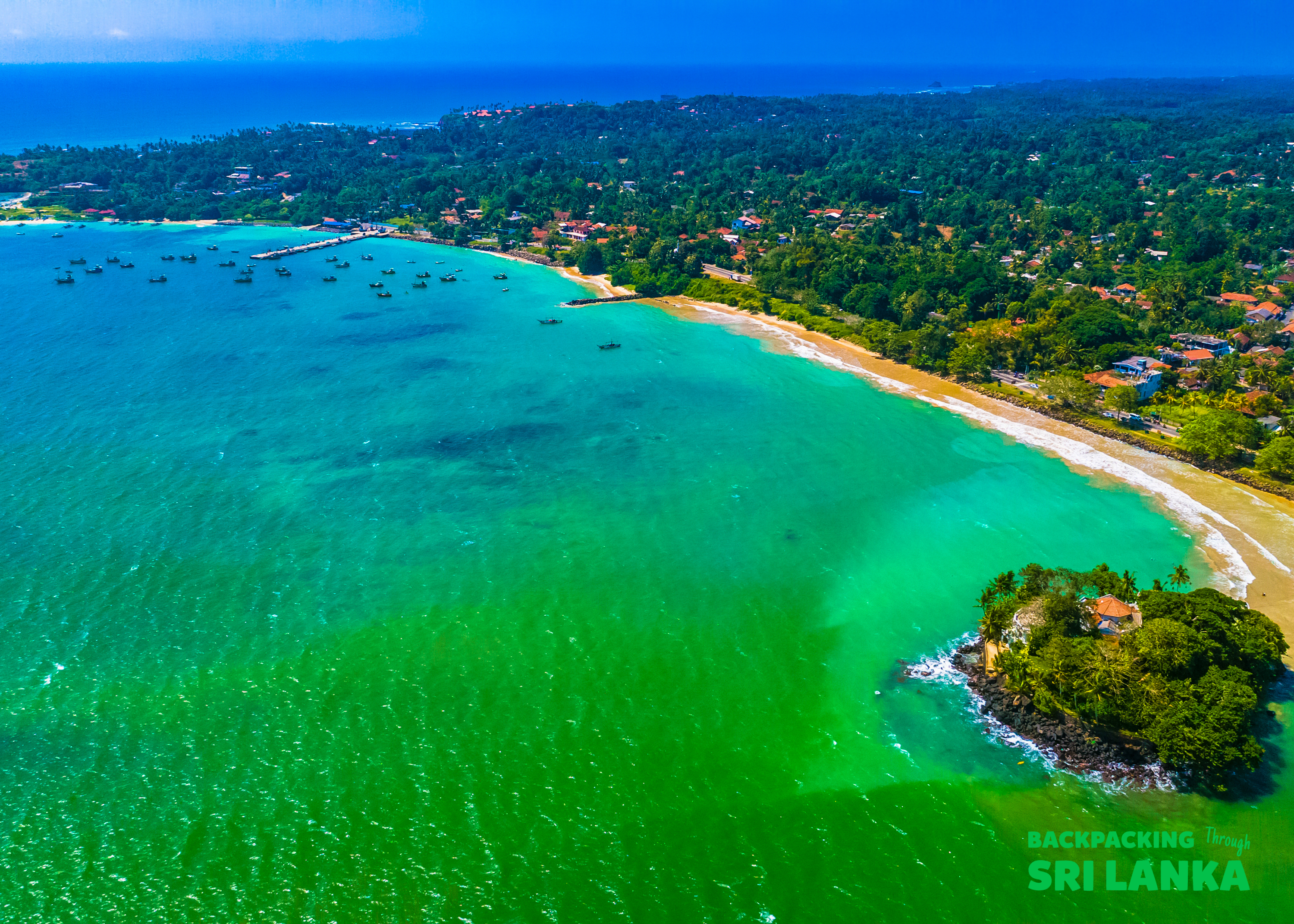 Beautiful aerial view of Weligama Bay, Sri Lanka, with turquoise ocean, a sandy beach, and a small island.