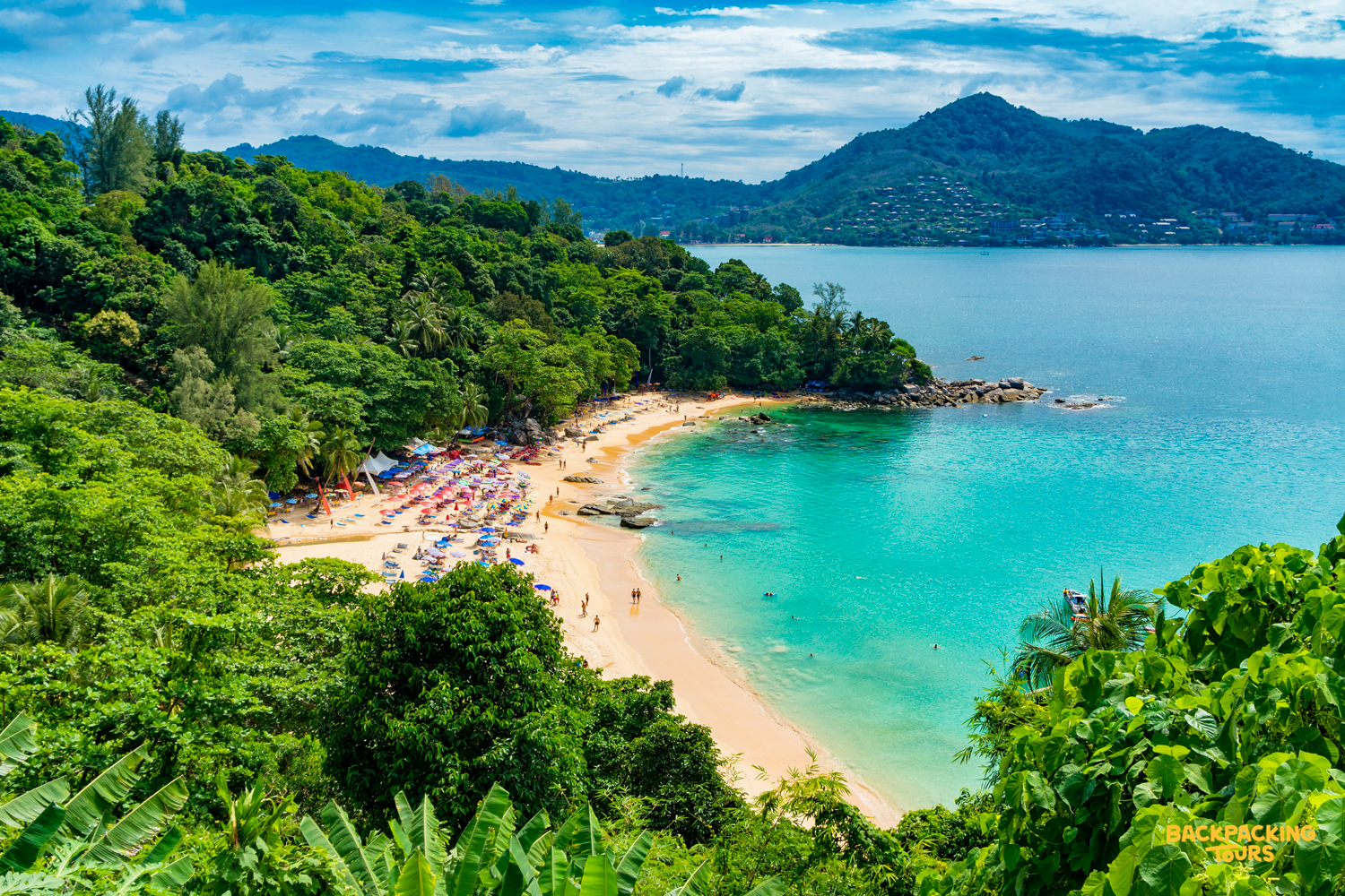 Stunning aerial view of a tropical beach with turquoise water and lush green hills in Phuket.