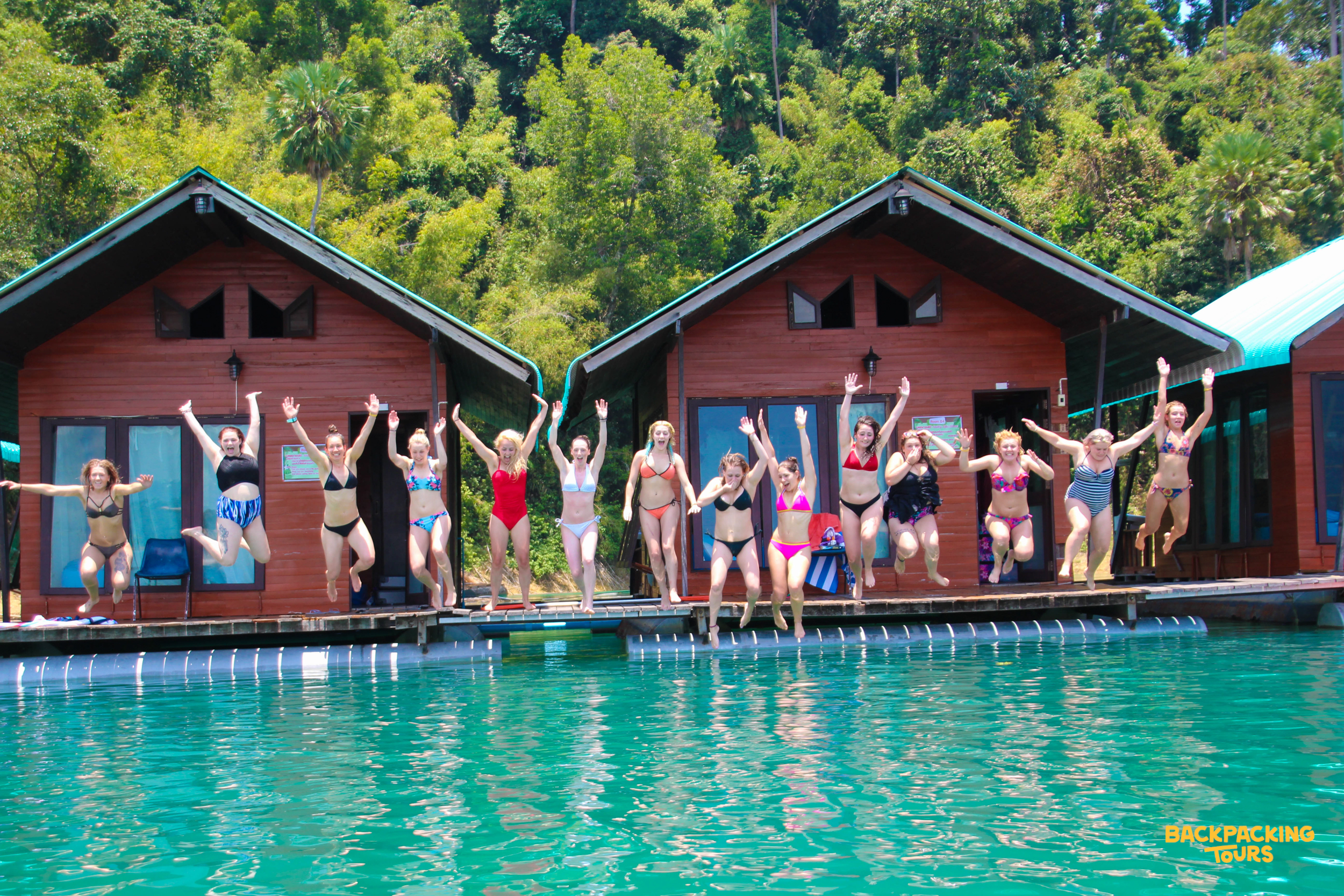 Group of backpackers jumping into Khao Sok lake from raft.