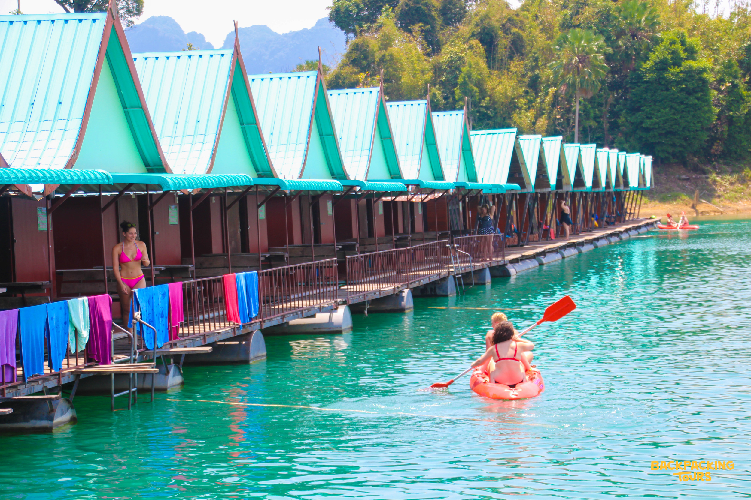 People kayaking and relaxing at floating bungalows on the stunning Cheow Lan Lake in Khao Sok National Park.