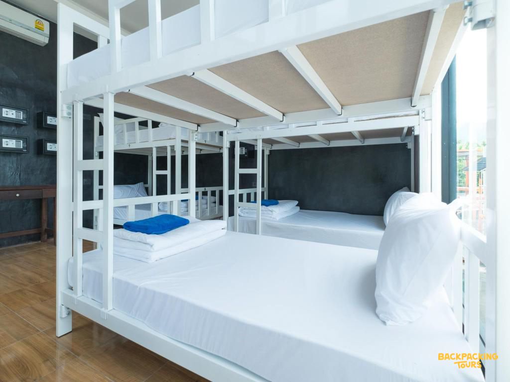 A clean and modern hostel dorm room with white bunk beds and fresh blue towels in Koh Phi Phi.